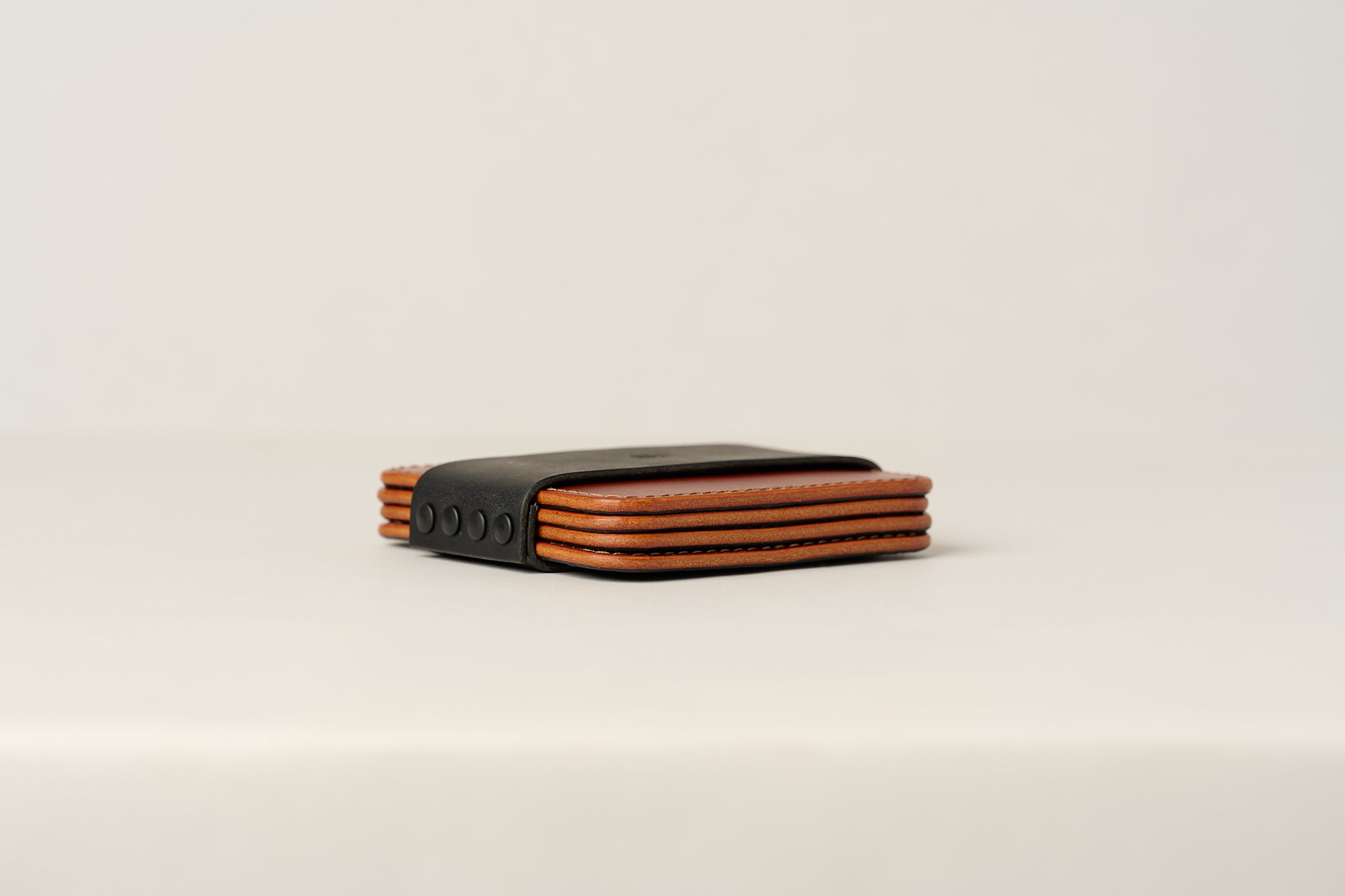 Brown leather coaster set shown in black storage sleeve.